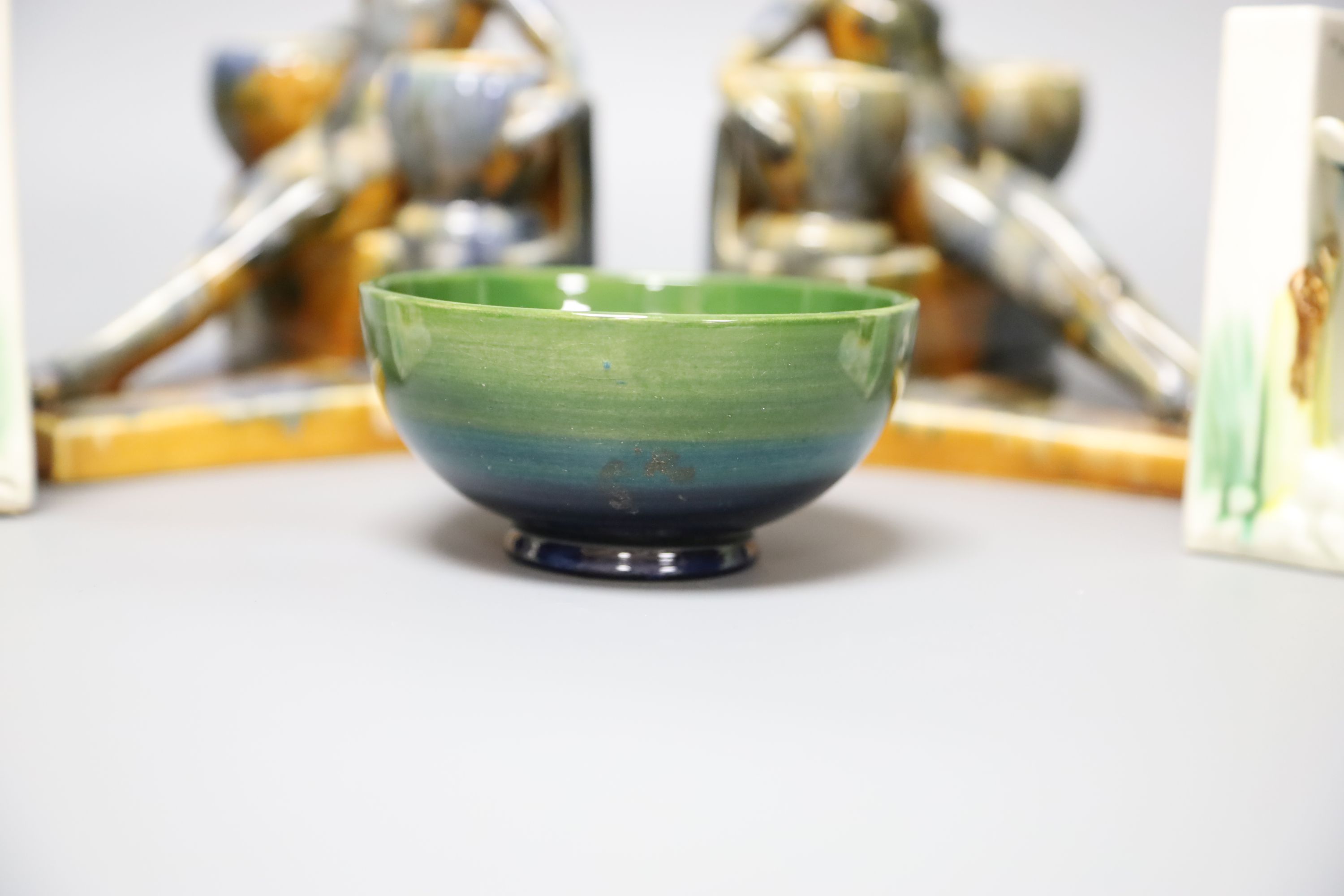 A Moorcroft green ground 'Columbine' pattern bowl, Dia 11cm and two pairs of ceramic bookends,